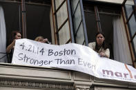 Marla Fogelman, right, hangs a banner on the second floor over Marathon Sports store, the site of the first bomb blast in 2013, before the start of the 118th Boston Marathon Monday, April 21, 2014 in Boston. (AP Photo/Charles Krupa)