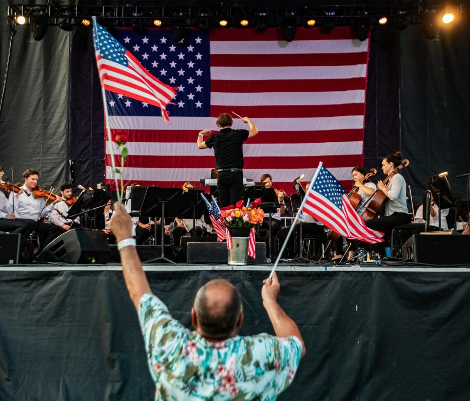 A man waved American flags while the Louisville Orchestra played during the Independence Day concert and fireworks show at Waterfront Park. July 4, 2021