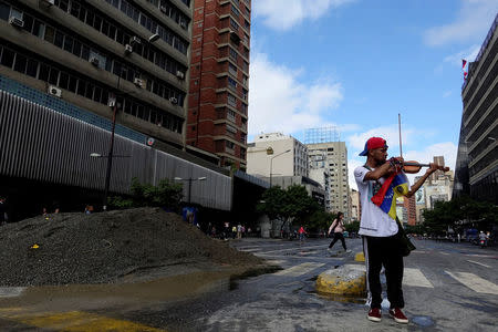 FILE PHOTO - Venezuelan violinist Wuilly Arteaga plays the violin next to a pile of sand used by protesters to block the street during a protest against Venezuelan President Nicolas Maduro's government in Caracas, Venezuela July 18, 2017. REUTERS/Carlos Garcia Rawlins
