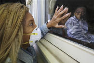 Camilla White visits her mother Lillian Barber, 90, from outside, seeing her through the window while touching fingertips through the glass at Cottage Landing Assisted Living on Tuesday, April 28, 2020, in Carrollton, Ga. White didn't discover there had been several deaths at the home from coronavirus and a significant outbreak until seeing the info on a state website and said that before the outbreak "I would go inside and just lay my head in her lap, but I can't do none of that anymore." (Curtis Compton/Atlanta Journal-Constitution via AP)