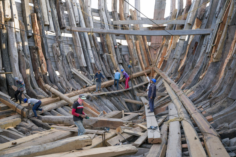 A crew works on a traditional ship under construction in Mandvi in Gujarat, India, Tuesday, Jan. 9, 2024. This 400-year-old tradition of shipbuilding using manual tools is in decline but a few ships are still built each year to be used for fishing and transporting goods. (AP Photo/Ashwini Bhatia)