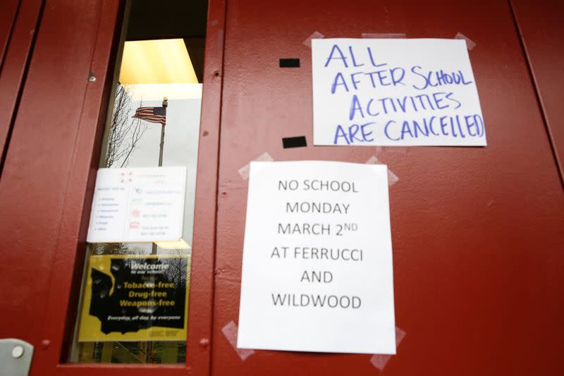 A US flag is reflected in a window as signs announcing a closure and cancelled activities are pictured at Ferrucci Junior High School after two schools were closed for cleaning due to flu-like symptoms of a relative in Puyallup