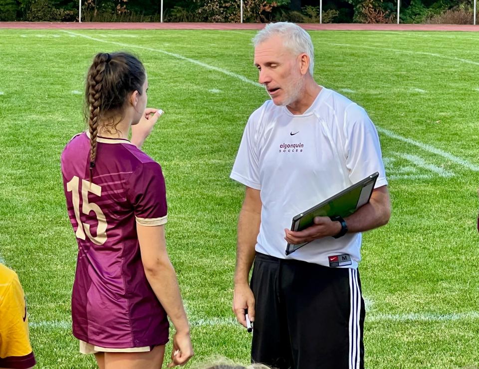 Algonquin girls' soccer coach John Frederick goes over halftime strategy with a player during halftime of Saturday's game against Acton-Boxborough.