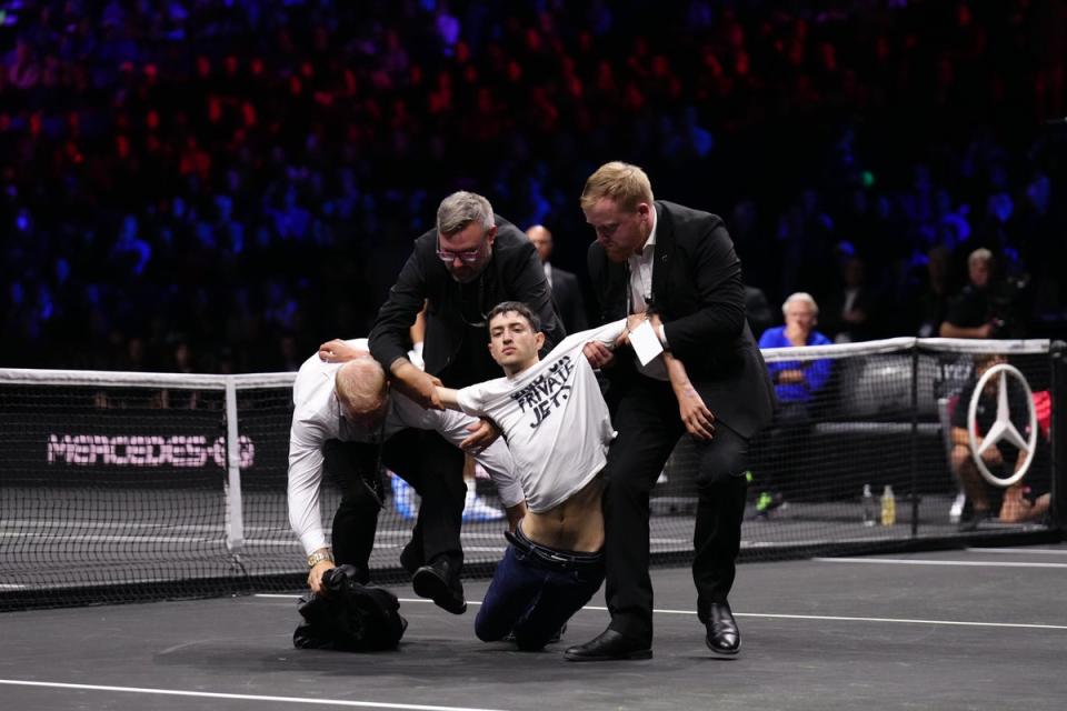 Stewards remove a protester who set fire to the court at the O2 Arena (John Walton/PA) (PA Wire)