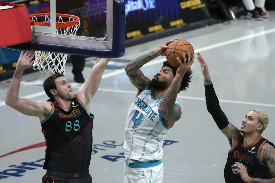 Charlotte Hornets center Nick Richards (4) looks to shoot over Washington Wizards forward Danilo Gallinari, left, and forward Kyle Kuzma during the first half of an NBA basketball game Friday, Nov. 10, 2023, in Washington. (AP Photo/Mark Schiefelbein)