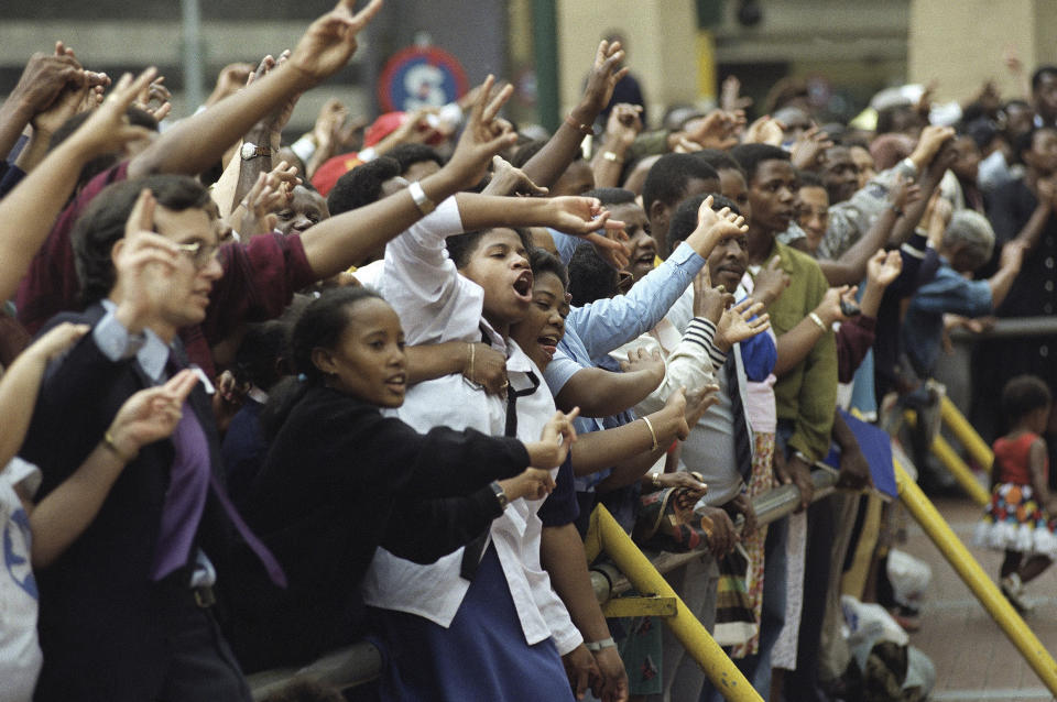 FILE — A crowd of people sing and give peace signs during a lunchtime peace march in downtown Johannesburg, South Africa, Jan. 27, 1994 ahead of the country's all race elections. South Africans celebrate "Freedom Day" every April 27, when they remember their country's pivotal first democratic elections in 1994 that announced the official end of the racial segregation and oppression of apartheid. (AP Photo/Denis Farrell/File)