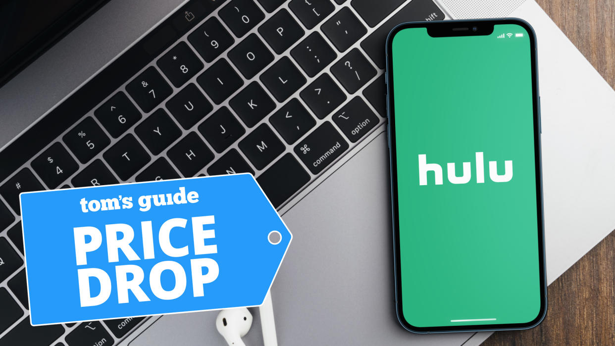  Hulu logo shown on iPhone lying on MacBook laptop 