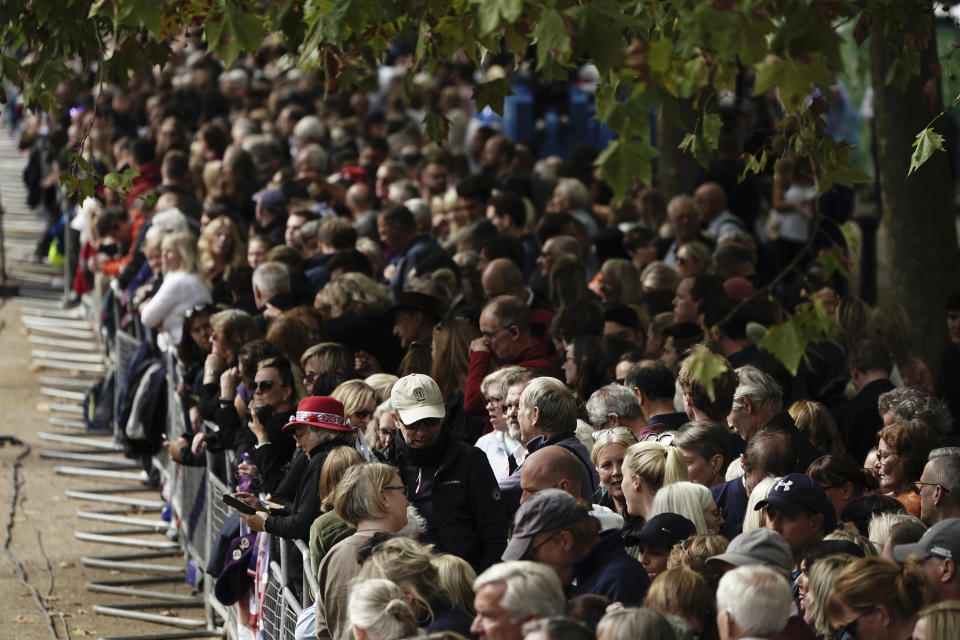 Crowds gather along the Mall ahead of the ceremonial procession of the coffin of Queen Elizabeth II from Buckingham Palace to Westminster Hall, London, Wednesday Sept. 14, 2022. The Queen will lie in state in Westminster Hall for four full days before her funeral on Monday Sept. 19. (Aaron Chown/Pool via AP)