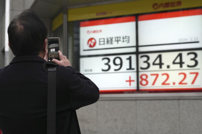 A person takes photograph an electronic stock board showing Japan's Nikkei 225 index at a securities firm Thursday, Feb. 22, 2024, in Tokyo. Japan’s benchmark Nikkei 225 index surged Thursday past the record it set in 1989 before its financial bubble burst, ushering in an era of faltering growth. (AP Photo/Eugene Hoshiko)