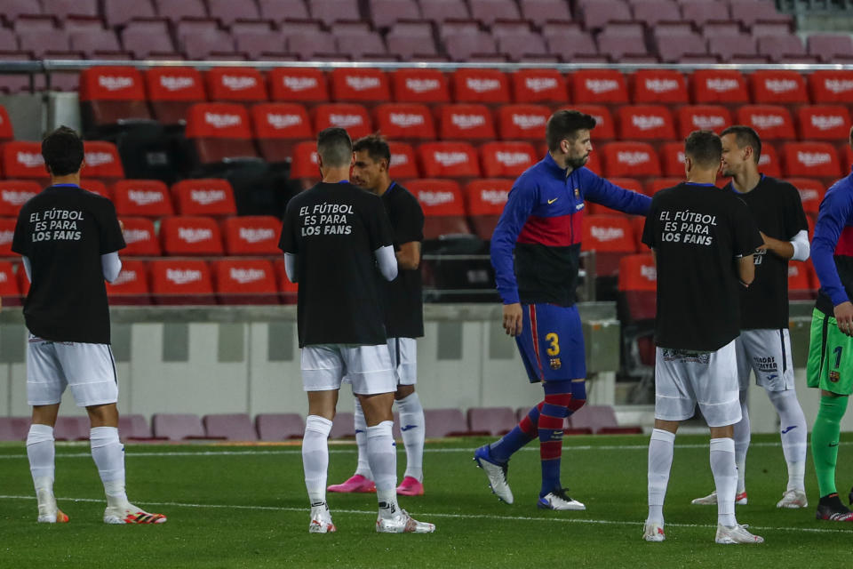 Los jugadores del Getafe visten camisetas con mensajes de protesta contra el proyecto de la Superliga, el jueves 22 de abril de 2021, antes de enfrentar al Barcelona (AP Foto/Joan Monfort)