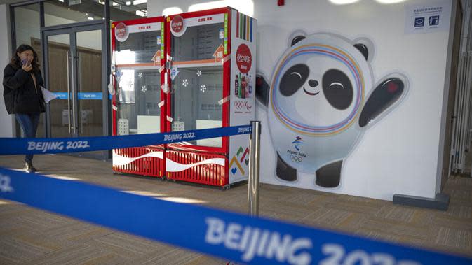 Seorang anggota staf berjalan melewati mural maskot Olimpiade Bing Dwen Dwen di Desa Olimpiade Musim Dingin, Beijing, China, Jumat, 24 Desember 2021. Olimpiade dan Paralimpiade Musim Dingin 2022 akan diadakan mulai bulan Februari. (AP Photo/Mark Schiefelbein)