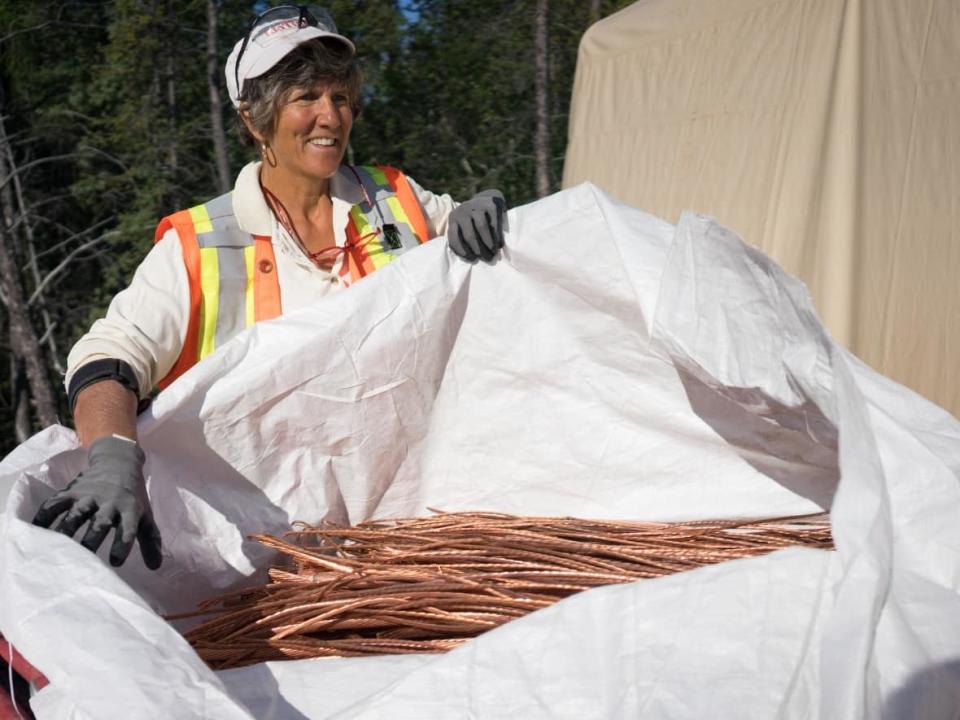 Diane Hach&#xe9; opens a bag to display a pile of stripped copper wire. She spends many days stripping the copper from the wiring and then sells it, giving the money to good causes. (Photo submitted by Rio Tinto - image credit)