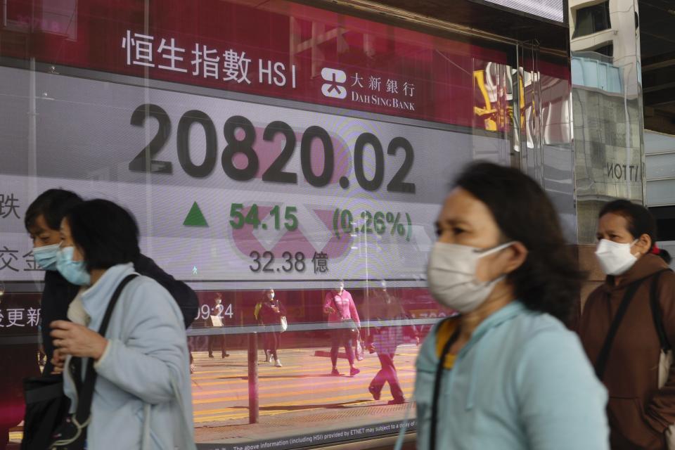 People walk past a bank's electronic board showing the Hong Kong share index at Hong Kong Stock Exchange Wednesday, March 9, 2022. Asian stocks rebounded Wednesday after Wall Street declined and China reported inflation edged higher. (AP Photo/Vincent Yu)