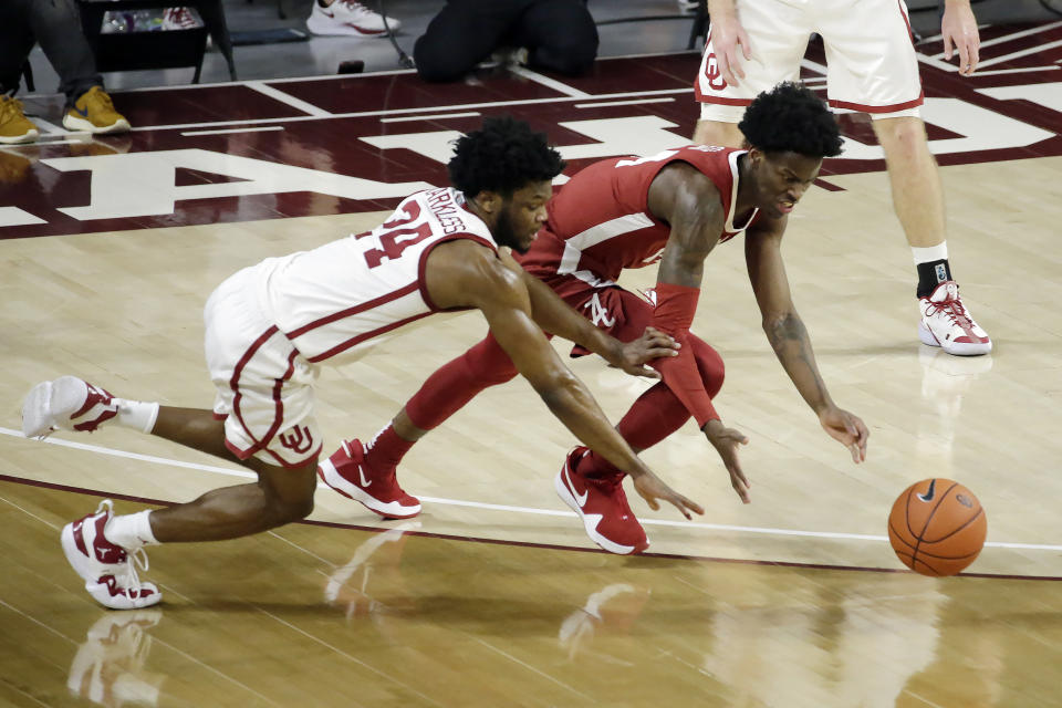 Oklahoma's Elijah Harkless (24) and Alabama's Keon Ellis (14) fight for the ball during the second half of an NCAA college basketball game in Norman, Okla., Saturday, Jan. 30, 2021. (AP Photo/Garett Fisbeck)