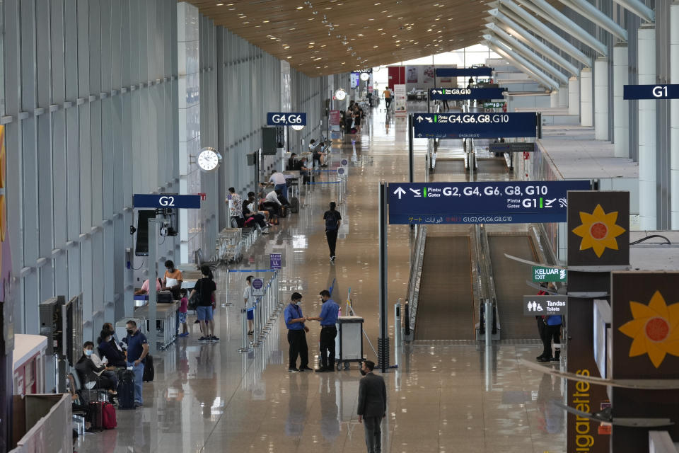 Travelers are seen waiting for flights at Kuala Lumpur International Airport in Sepang, Malaysia, Friday, April 1, 2022. Malaysia's international borders open to foreigners on Friday and fully vaccinated travelers do not have to undergo quarantine. (AP Photo/Vincent Thian)