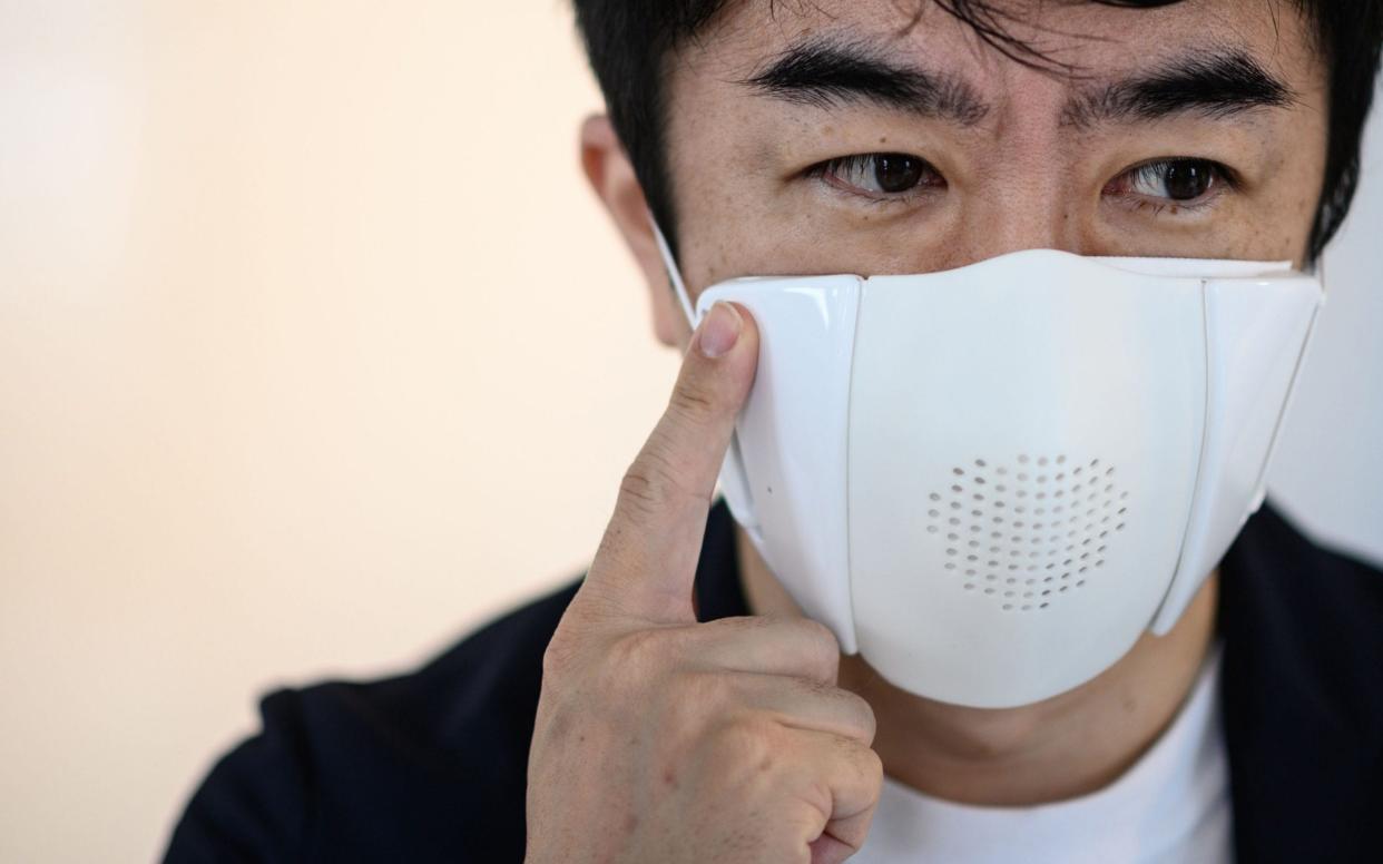 Donut Robotics chief executive Taisuke Ono poses for a photo wearing the company's smart face mask - Philip Fong/AFP