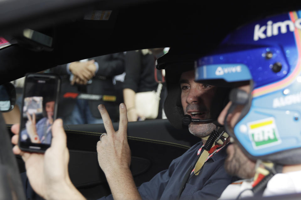 Mclaren driver Fernando Alonso of Spain, right, takes pictures of Nascar World champion Jimmie Johnson before driving a McLaren 570S car at the Yas Marina racetrack in Abu Dhabi, United Arab Emirates, Saturday, Nov. 24, 2018. Seven-time NASCAR champion Jimmie Johnson and two-time Formula One champion Fernando Alonso drive Pirelli hot laps together around the Abu Dhabi F1 track on Saturday afternoon. (AP Photo/Luca Bruno)