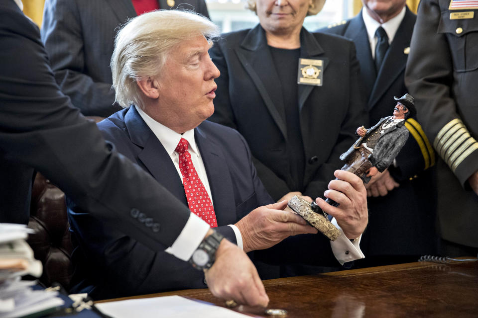 President Donald Trump looks at a statue he received as a gift while meeting with county sheriffs in the Oval Office of the White House on Feb. 7, 2017.