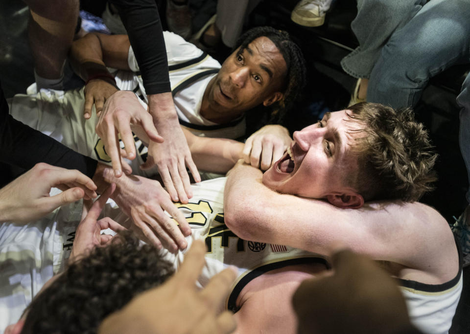 Wake Forest forward Andrew Carr, center, is hugged by teammates Lucas Taylor, left, and Cameron Hildreth (2) after Carr scored the game winning shot at the buzzer in the second half of an NCAA college basketball game against Appalachian State on Wednesday, Dec. 14, 2022, at Joel Coliseum in Winston-Salem, N.C. (Allison Lee Isley/The Winston-Salem Journal via AP)