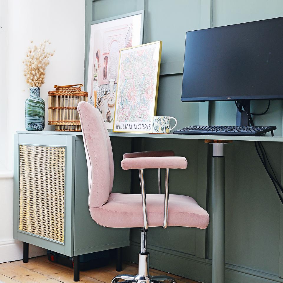 Home office with teal furniture, rattan cupboard and pink chair.