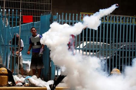 A demonstrator throws back a tear gas canister while clashing with riot security forces during a strike called to protest against Venezuelan President Nicolas Maduro's government in Caracas, Venezuela, July 20, 2017. REUTERS/Carlos Garcia Rawlins