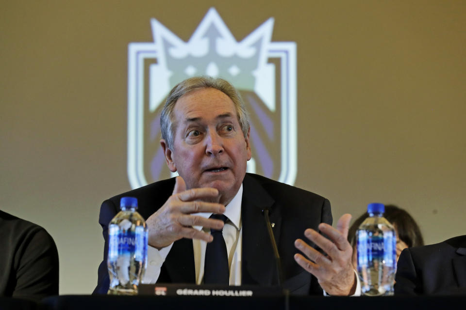 OL Groupe's Gerard Houllier sits in front of the Rein FC team logo as he speaks, Thursday, Dec. 19, 2019, during a news conference to announce that OL Groupe, the parent company of Olympique Lyonnais, is buying the National Women's Soccer League's Reign FC team in a transaction expected to close in January 2020. Reign FC will continue to play its home games at Cheney Stadium, the venue it shares with the Triple-A minor league baseball team the Tacoma Rainiers. (AP Photo/Ted S. Warren)