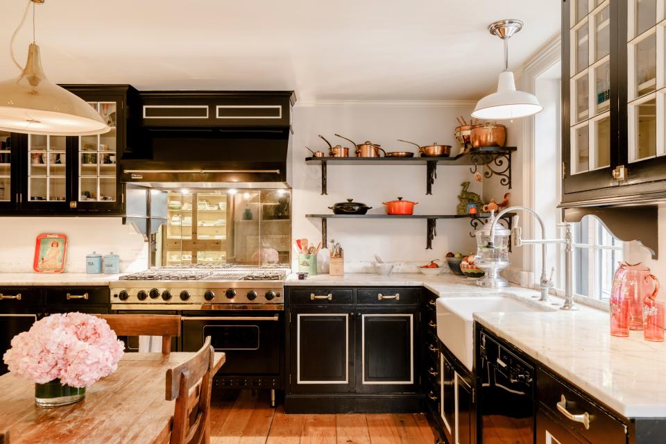 The home’s kitchen look, feel, and layout was inspired by a photograph Tyler and Pentreath had come across of cabinet with very deep green—almost black—paint and white piping, next to a wooden table. “It was something I really loved,” says Tyler. “We designed the whole kitchen around that.” Tyler opted to keep the kitchen on the ground floor—as it would have been when the townhouse was built at the turn of the 19th century. “It’s so cozy down there, and you can go out into the garden to eat, as well.” While the working mom of three is not necessarily hosting dinner parties all the time, Tyler says, “We are cooking all the time. Everybody is always coming in—eating and snacking and squeezing around the table.” The light fixture above the table is a vintage 1940s lamp designed by Paavo Tynell of Finland.