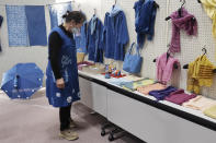 In this image from video, Kiyoko Mori, 65, the head of indigo dye group called Japan Blue, looks at displayed indigo dyed artwork at a community center where residents evacuated when the massive earthquake hit the area in 2011, in Minamisoma, Fukushima Prefecture, northeastern Japan, on Feb. 20, 2021. After the Fukushima nuclear plant disaster a decade ago, nearby farmers weren't allowed to grow crops for two years because of radiation. After the restriction was lifted, two farmers in the town of Minamisoma found an unusual way to rebuild their lives and help their destroyed community. Mori and Yoshiko Ogura planted indigo and soon began dying fabric with dye produced from the plants. (AP Photo/Chisato Tanaka)