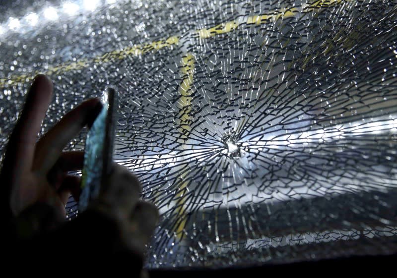 Journalists look at the window of a bus reportedly hit by bullets. (Reuters)