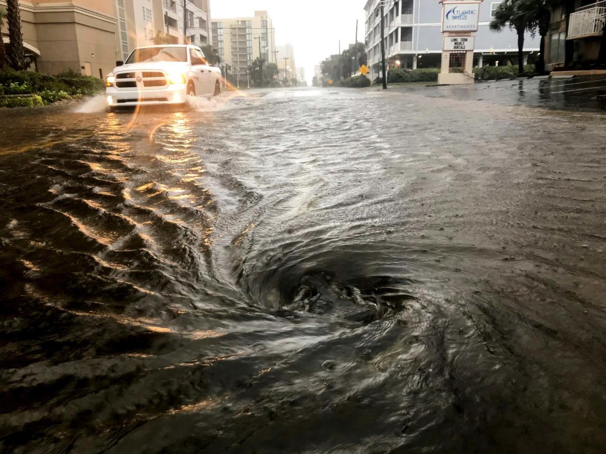 Floodwaters swirl around a storm drain: AP