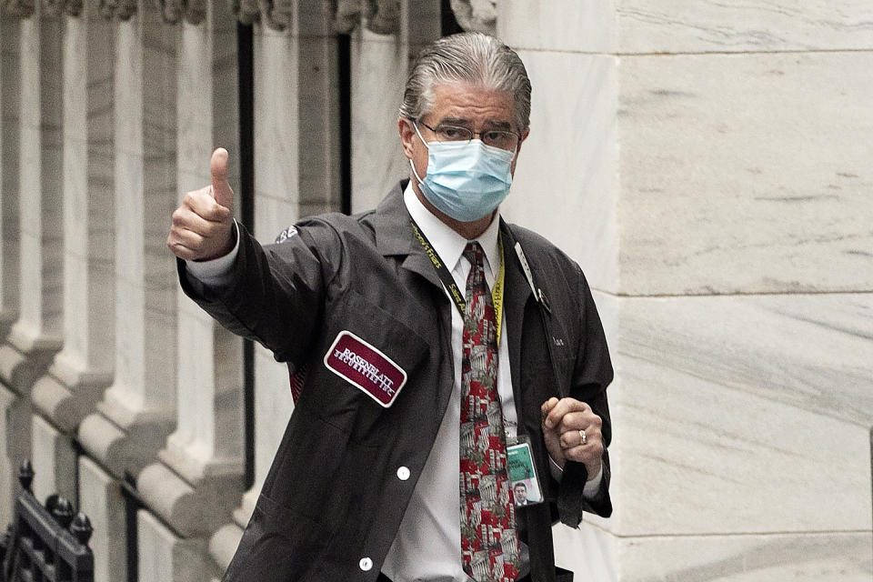 Trader Daniel Krieger signals a thumbs-up as he arrives at the New York Stock Exchange where the trading floor reopens, Tuesday, May 26, 2020. (AP Photo/Mark Lennihan)