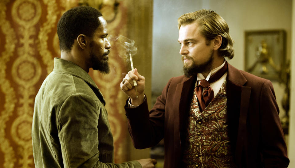 Django Unchained: A man holds a smoking cigarette threateningly in front of another man's face