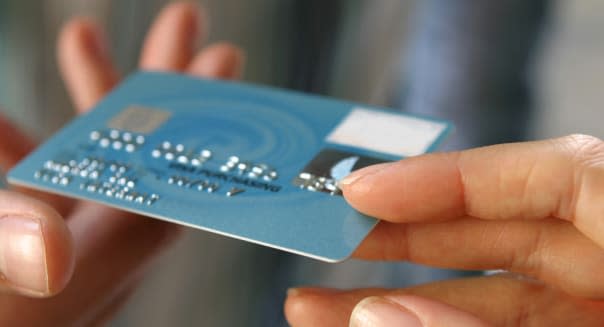 Hand passing a payment card (N.B. Mocked up details*)