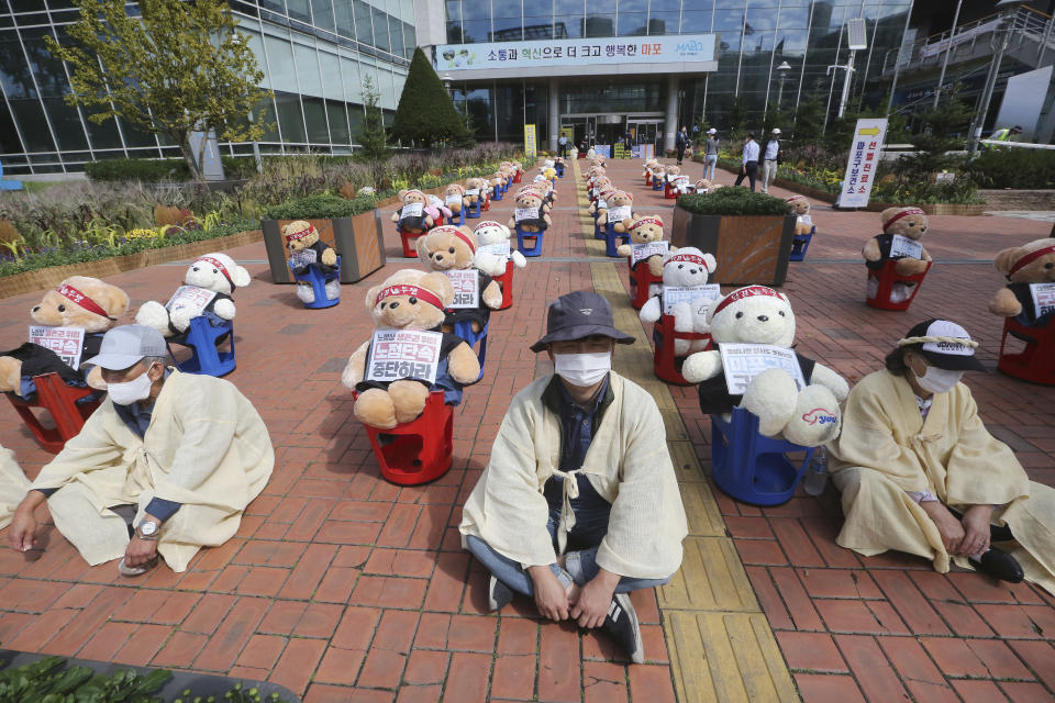 Street vendors sit to protest against a crackdown on illegal street vendors, in front of the Mapo ward office in Seoul, South Korea, Thursday, Sept. 24, 2020. They replaced protestors with teddy bears to avoid the violation of an ongoing ban on rallies with more than 10 people amid the coronavirus pandemic. The signs read: "Stop crackdown." (AP Photo/Ahn Young-joon)