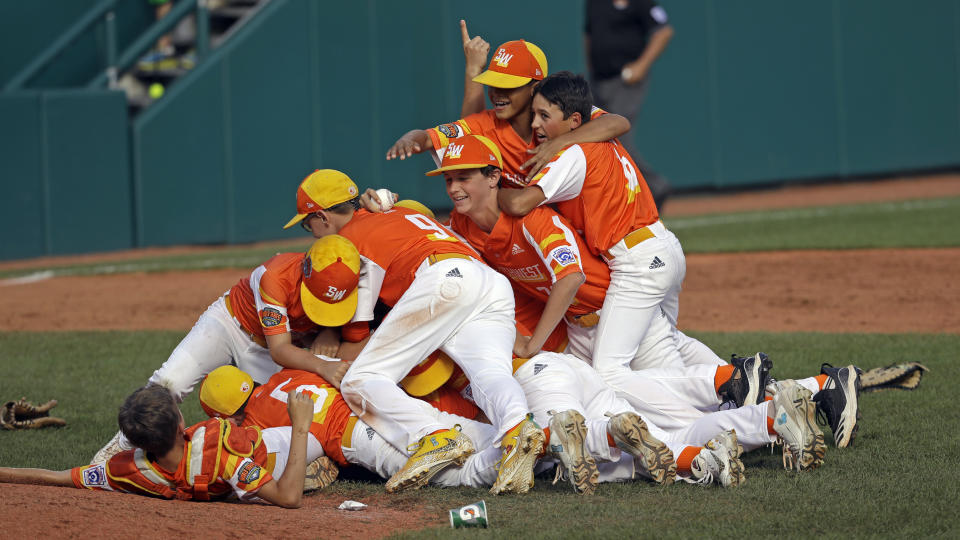 River Ridge, Louisiana's Stan Wiltz embraces Peyton Spadoni (6) as they jump on top of Jeffrey Curtis and Conner Perrot (9) on top of the pile as they celebrate the 8-0 win against Curacao in the Little League World Series Championship game in South Williamsport, Pa., Sunday, Aug. 25, 2019. (AP Photo/Tom E. Puskar)