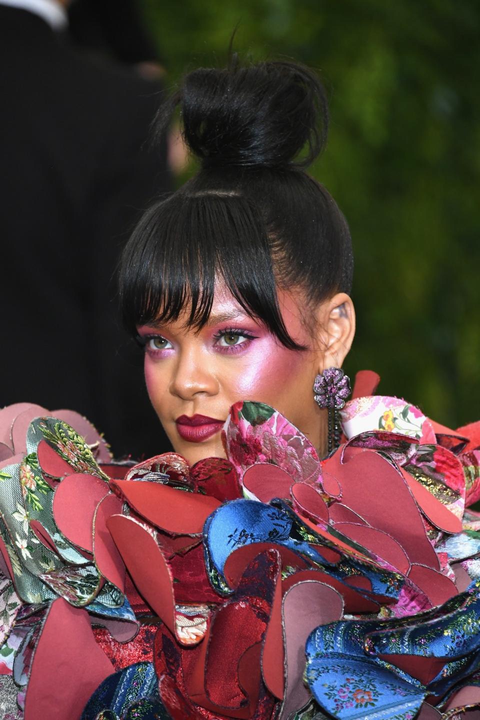 <p>RiRi shut down the Met Gala red carpet with her fuchsia holographic blush, slick bangs and simple topknot hairstyle, and ravishing deep-red lip color. (Photo: Getty Images) </p>