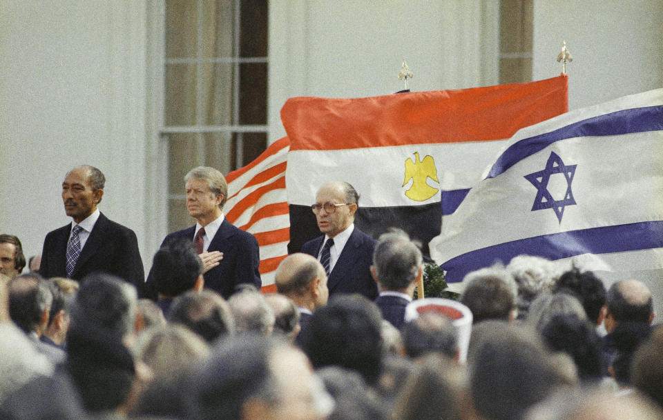 FILE - In this March 26, 1979 file photo, U.S. President Jimmy Carter, center, Egyptian President Anwar Sadat, left, and Israeli Prime Minister Menachem Begin stand in front of the billowing national flags of the U.S., Egypt, and Israel, as the national anthems are played, before the signing of the peace treaty between Israel and Egypt at the White House in Washington. This climactic event and others in 1979, which dominated television sets and newspaper front pages 40 years ago, helped shape the modern Middle East. (AP Photo, File)