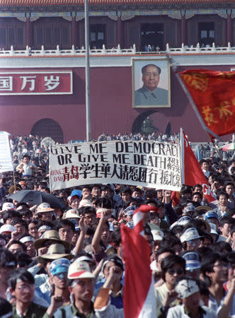 FILE PHOTO: Chinese students carry a sign that reads, "Give me democracy or give me death," during a demonstration in Tiananmen Square in Beijing, China, May 14, 1989. REUTERS/Dominic Dudouble/File Photo