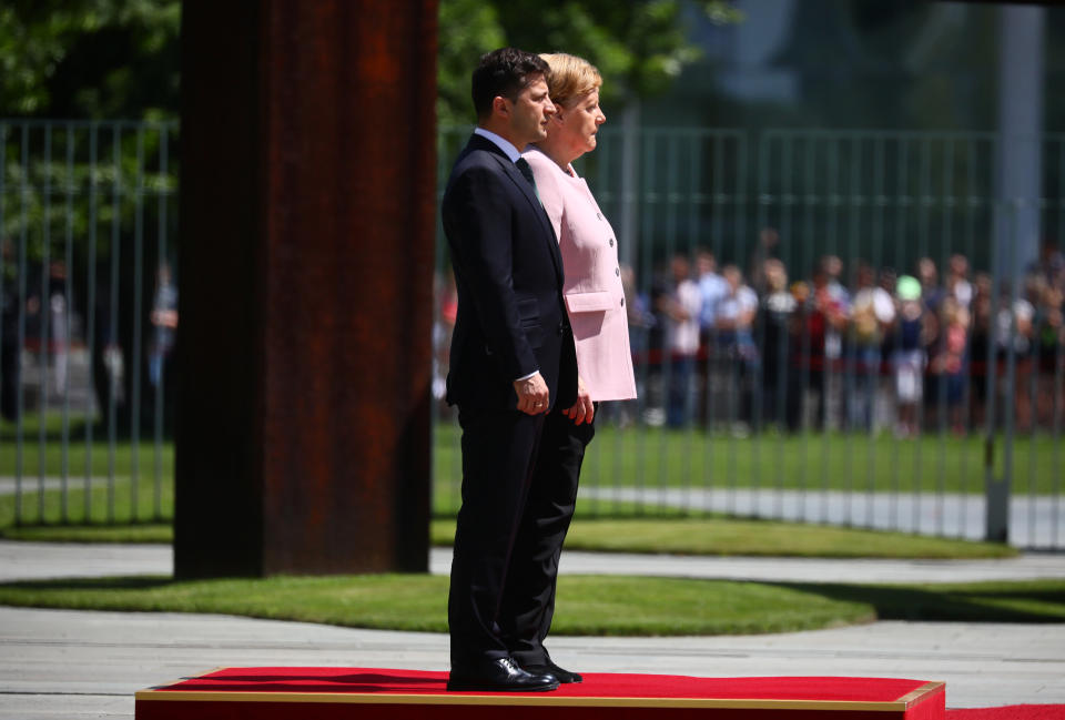 German Chancellor Angela Merkel and Ukrainian President Volodymyr Zelenskiy listen national anthems at the Chancellery in Berlin. REUTERS/Hannibal Hanschke