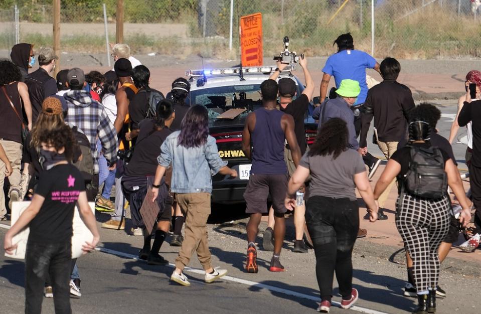 美國各地非裔族群對經過的警車踢打，甚至將窗戶打破。   圖：達志影像/美聯社