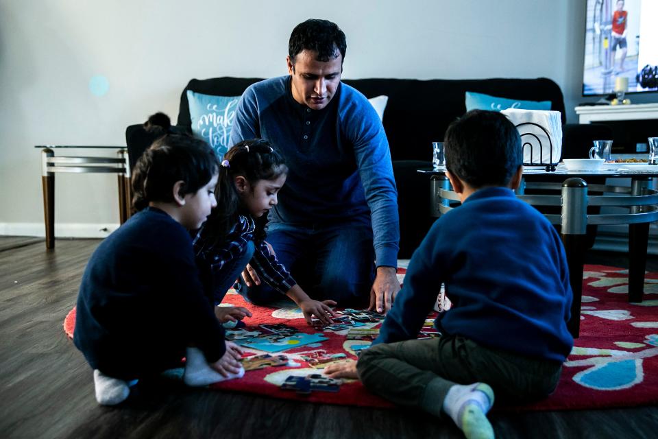 Hamayoon Azizi looks at a workbook with his children as they put together a puzzle at their home in Iowa City.