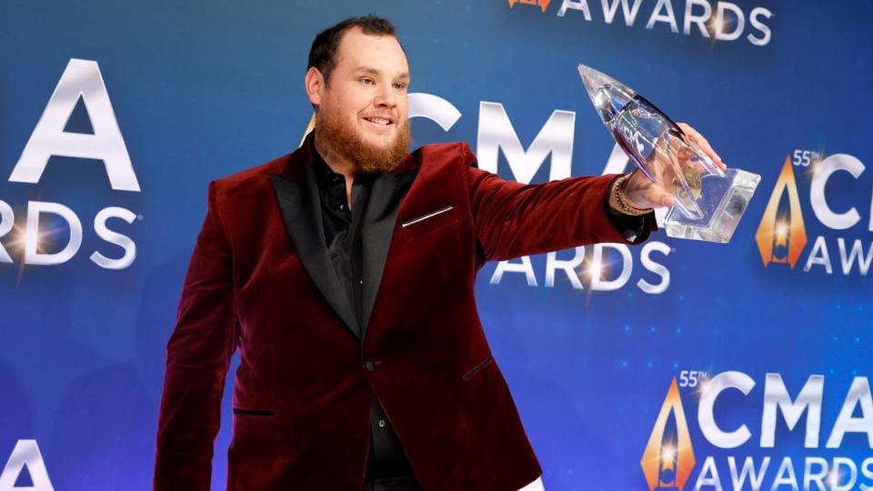 Man holding an award ; Luke Combs greatest hits