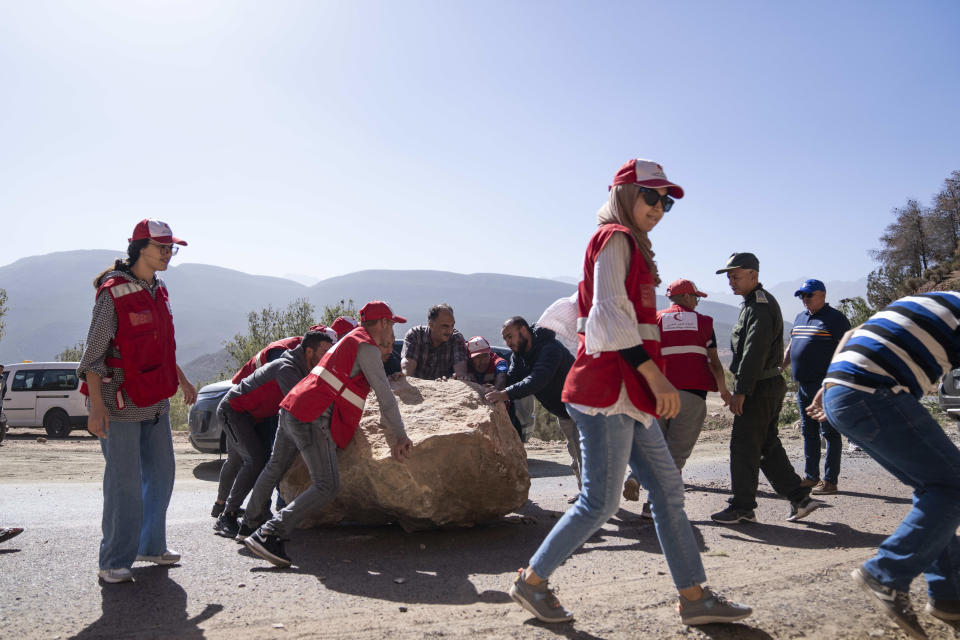 Moroccan Red Crescent workers help remove large stones which fell on roads during an earthquake, on the way to affected villages in the Middle Atlas mountain, near Marrakech, Morocco, Saturday, Sept. 9, 2023. A rare, powerful earthquake struck Morocco late Friday night, killing more than 800 people and damaging buildings from villages in the Atlas Mountains to the historic city of Marrakech. But the full toll was not known as rescuers struggled to get through boulder-strewn roads to the remote mountain villages hit hardest. (AP Photo/Mosa'ab Elshamy)