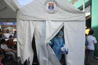 Medical Technologist Erika Alvarado comes out of a tent after she performs a COVID-19 test on a patient outside a hospital in Manila, Philippines on Friday, Dec. 24, 2021. In the Philippines, one of the worst-hit by the pandemic in Southeast Asia, daily COVID-19 infections have considerably dropped from an average 22,000 cases just three months ago during an alarming spike set off by the delta variant to just a few hundred in recent days after a delayed vaccination campaign considerably intensified with more vaccine shipment deliveries. (AP Photo/Aaron Favila)