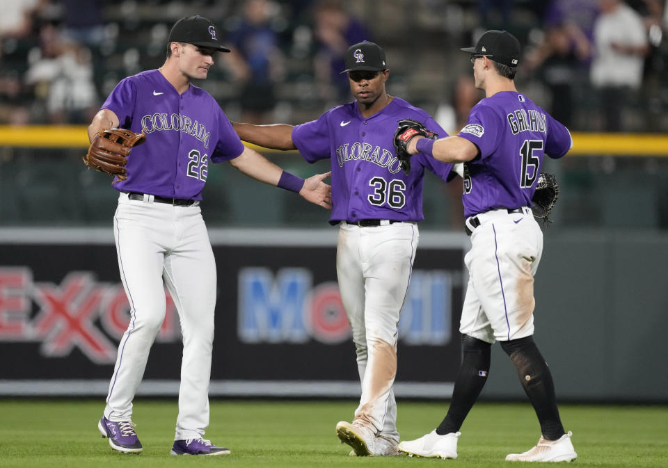 From left, Colorado Rockies left fielder Sam Hilliard, center fielder Wynton Bernard and right fielder Randal Grichuk celebrate after the ninth inning of a baseball game against the Texas Rangers Tuesday, Aug. 23, 2022, in Denver. (AP Photo/David Zalubowski)
