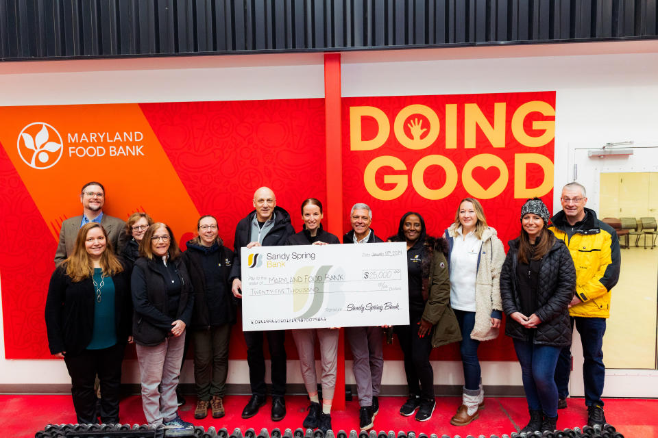 Sandy Spring Bank volunteers at the Maryland Food Bank. Check presentation photo in front of Maryland Food Bank signage in the warehouse.