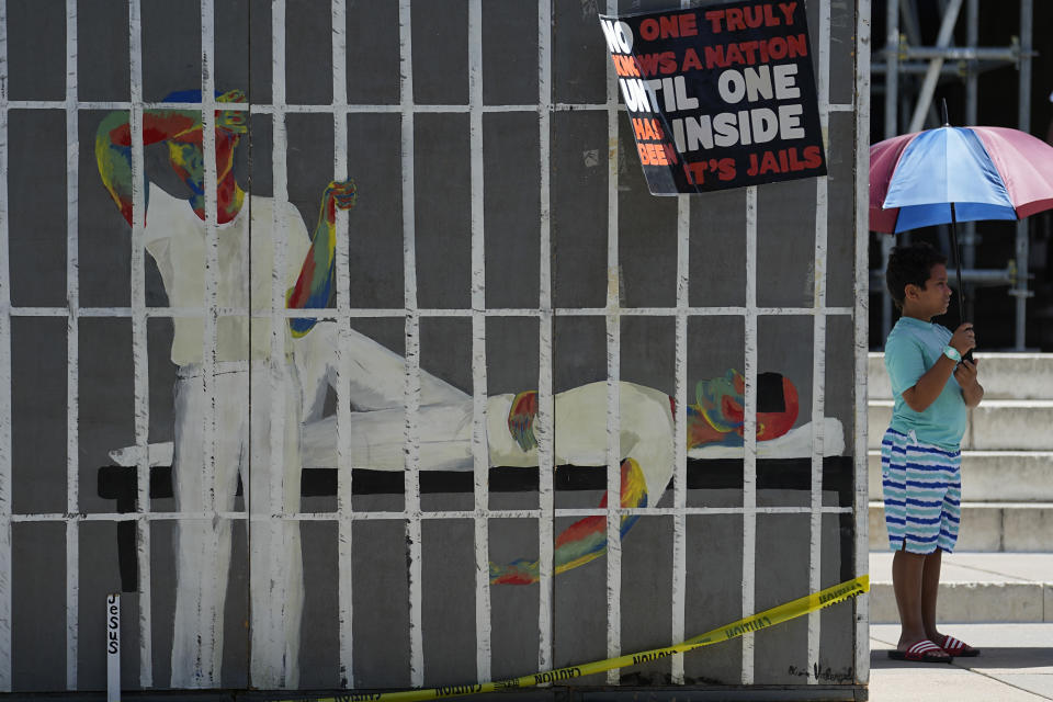 A boy stands near a makeshift prison cell during a rally on the steps of the Texas Capitol, Tuesday, July 18, 2023, in Austin, Texas. The group is calling for an emergency special session to address the deadly heat effecting inmates at Texas prisons. (AP Photo/Eric Gay)