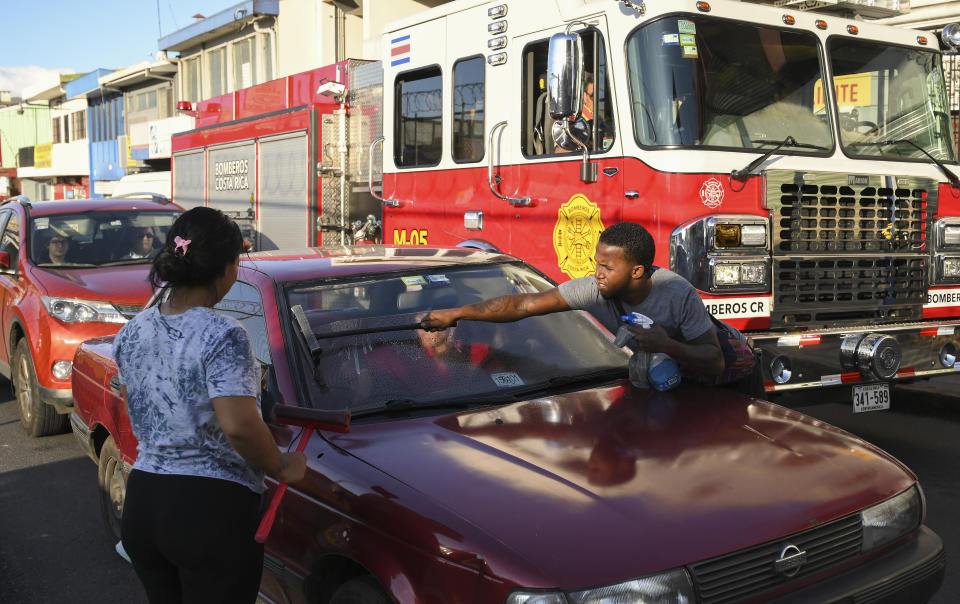 Venezuelan migrants Richard Plaza and his wife Widner Bijarena wash windshields on a street in San Jose, Costra Rica, Wednesday, Dec. 7, 2022. Faced with an overwhelmed asylum system, Costa Rica, one of the world’s great refuges for those fleeing persecution, is tightening its generous policies after President Rodrigo Chaves said the country’s system is being abused by economic migrants. (AP Photo/Carlos Gonzalez)