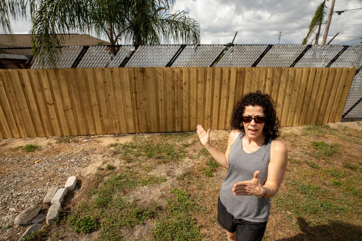 Tina Murray stands near the privacy fence she recently had installed at the edge of her son's yard in Auburndale. She and her son, John Murray, say their neighbors have been harassing them for months with incessant noise and other tactics.