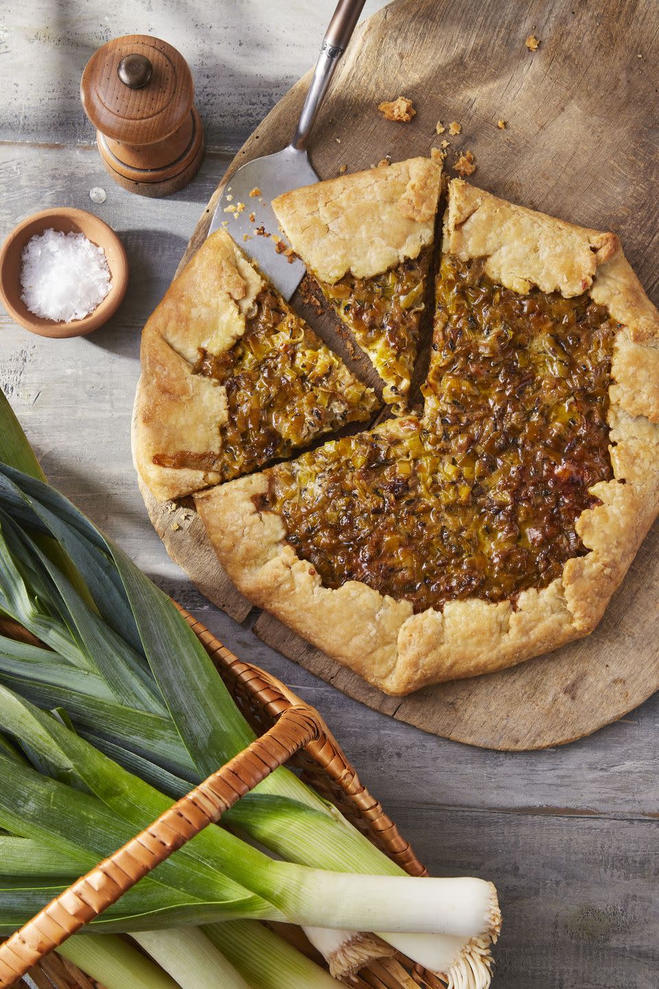 buttered leek and gruyère galette on a wooden serving board with two slices cut